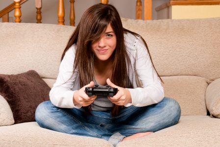 Jeune femme qui joue à la console sur un sofa